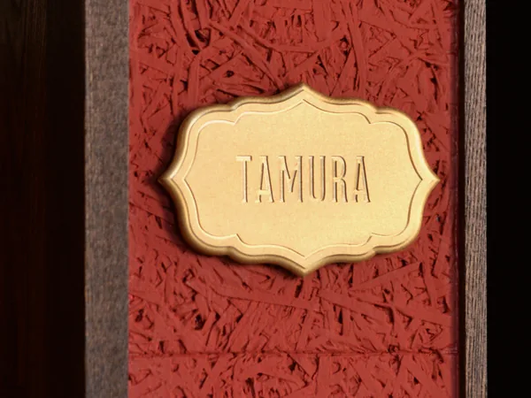 赤い壁に取り付けたTAMURAの真鍮表札 120×80mm SLIM