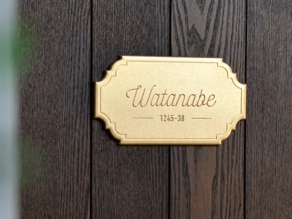 木の壁に取り付けたWATANABEの真鍮表札 180×100mm SLIM