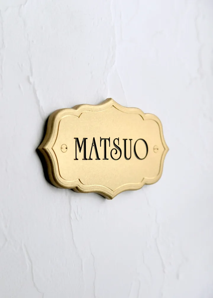 横長のかたちに表情のある書体を使ったMATSUOの真鍮表札。黒文字と真鍮ビス